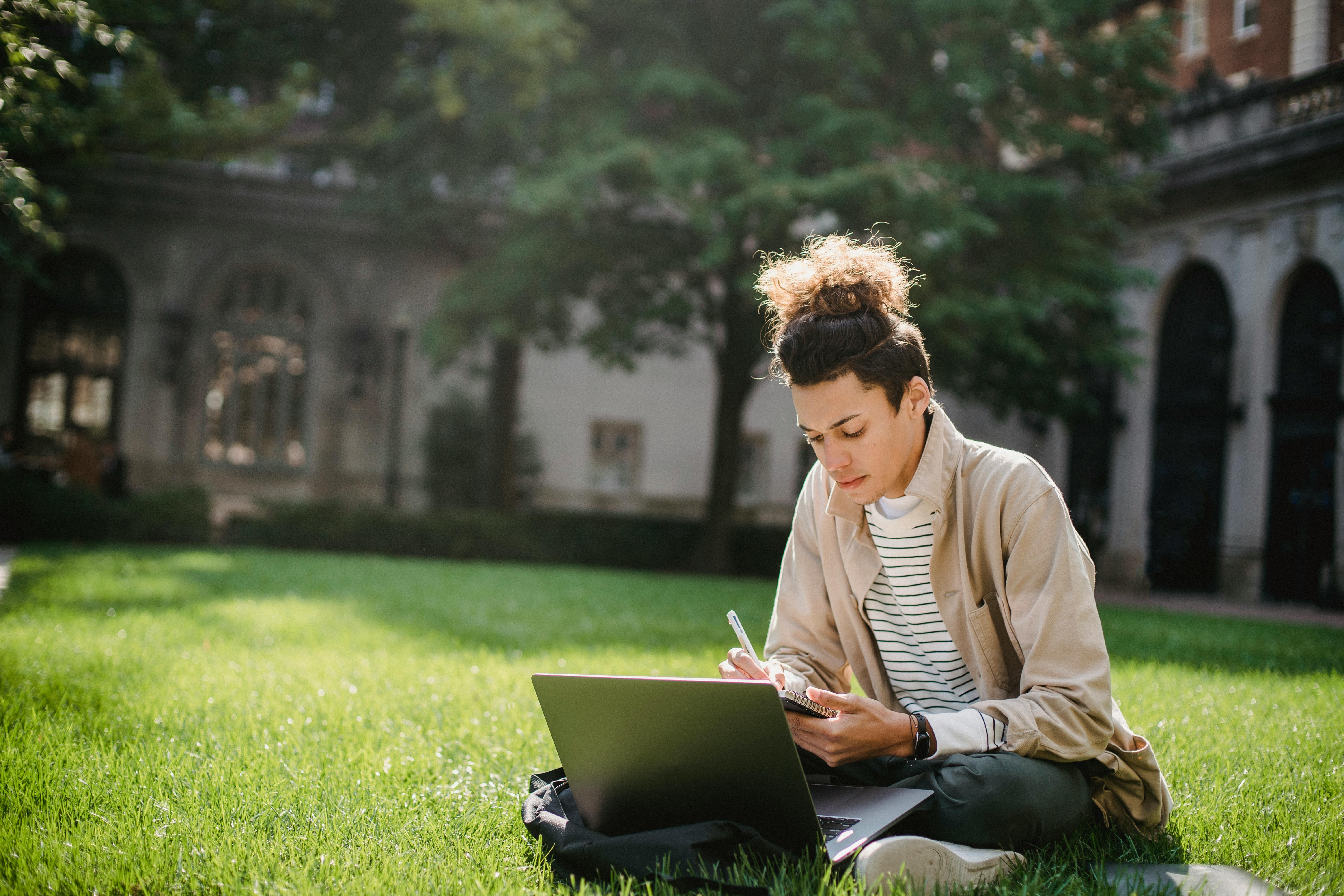 A university student studing on grass